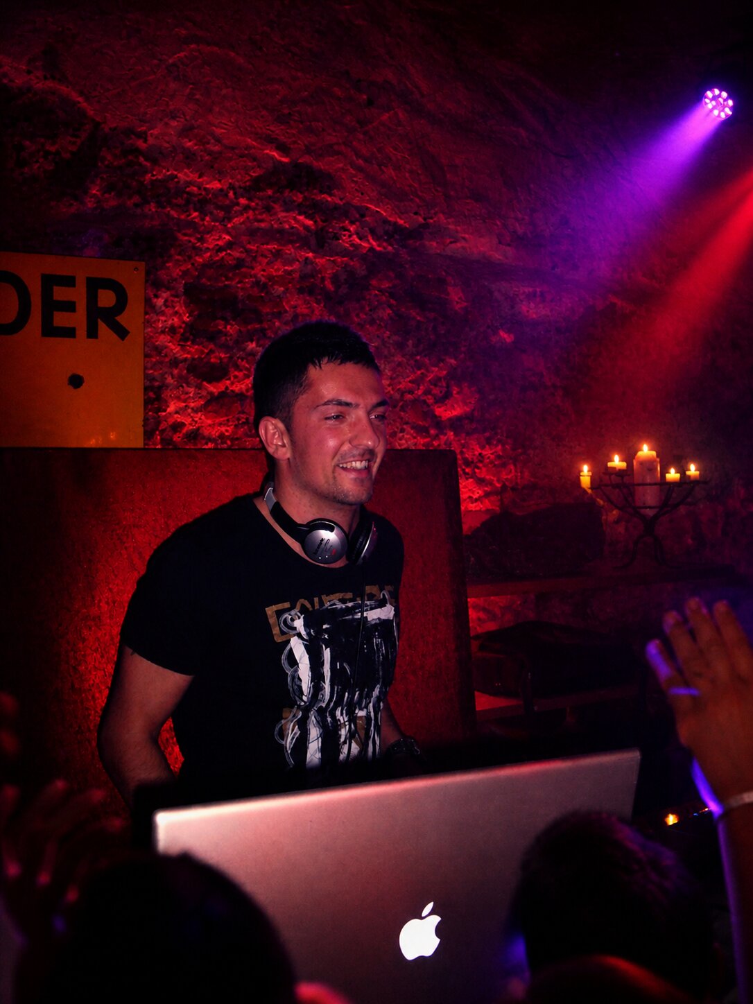 DJ Saint-Tropez dans une cave voûtée éclairée en rouge, ambiance intime aux chandelles
