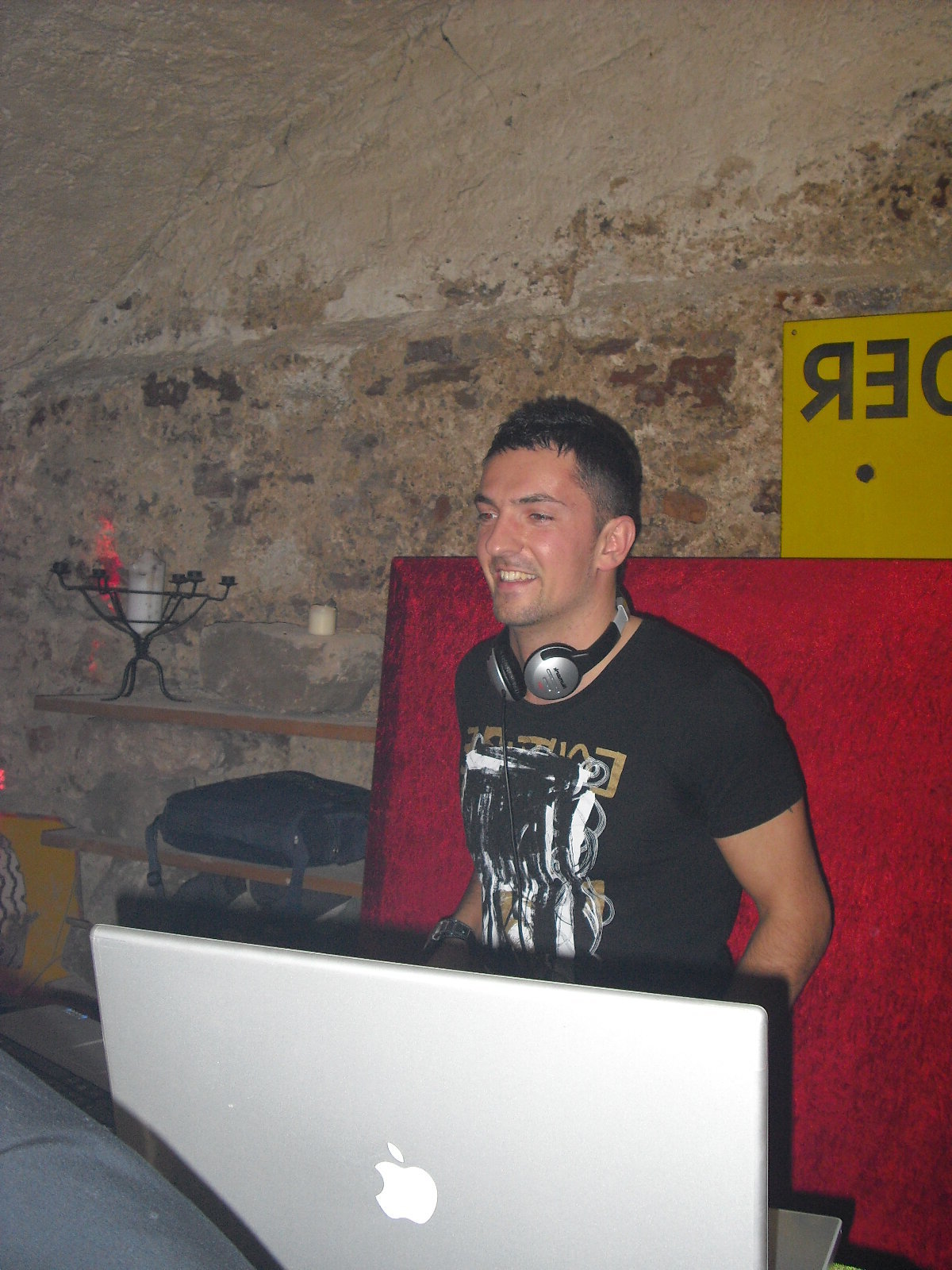 DJ Saint-Tropez souriant aux platines dans une cave voûtée en pierre