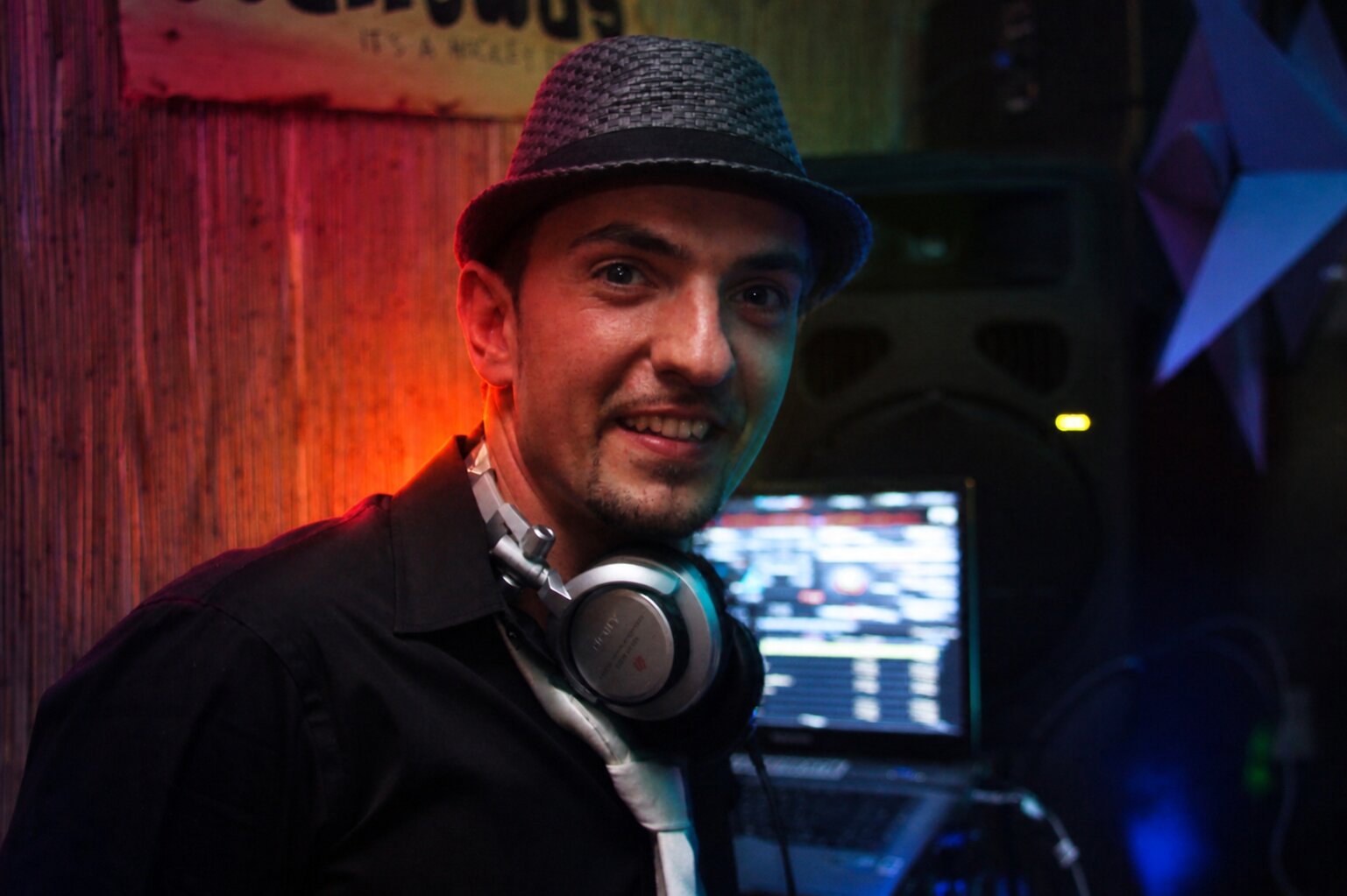 DJ Saint-Tropez avec chapeau fedora et casque audio en club