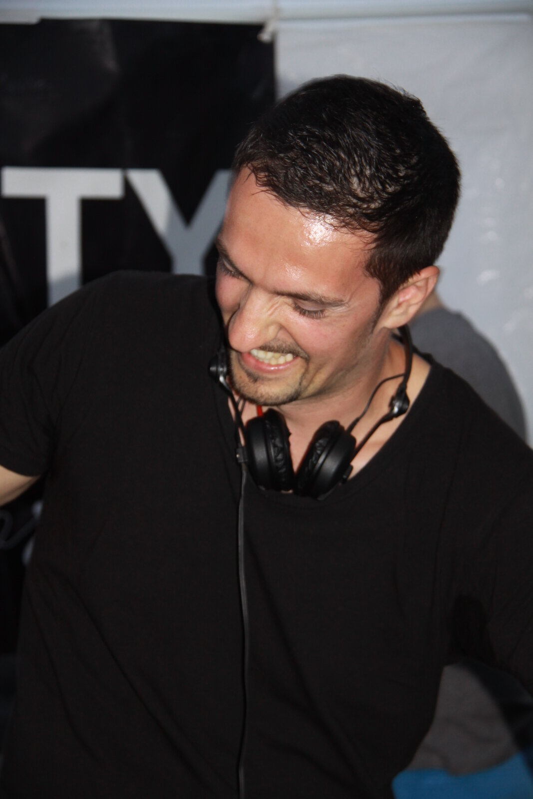 DJ Saint-Tropez en t-shirt noir, casque autour du cou, ambiance fin de soirée
